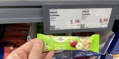 Ruka držící müsli tyčinku před regálem v supermaretu