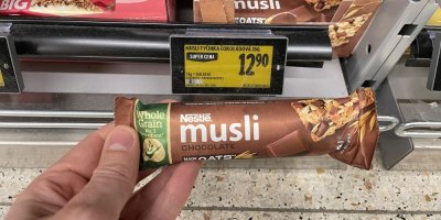 Ruka držící müsli tyčinku před regálem v supermaretu