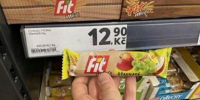 Ruka držící müsli tyčinku před regálem v supermaretu