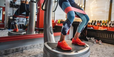 Žena cvičící na vibrační plošině 