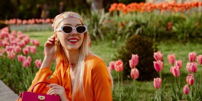 Žena ve slunečních brýlích a šátku venku u tulipánů