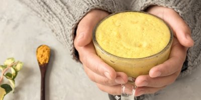 Žena drží hrnek zlatého mléka 