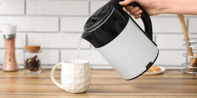 Žena nalévá horkou vodu z varné konvice do hrnku