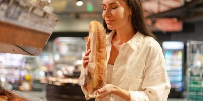 Žena si v supermarketu užívá vůni čerstvé bagety