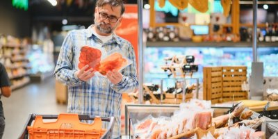 Muž se dívá na salámy v obchodě