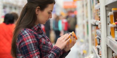 Žena čte etiketu medu v supermarketu