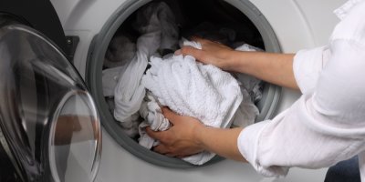 Žena vytahuje čisté bílé prádlo z pračky