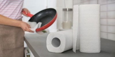 Žena utírá kuchyňskou pánev papírovou utěrkou