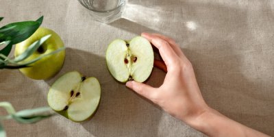 Ženská ruka a rozkrojené zelené jablko