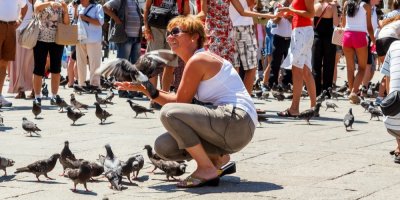 Žena obklopená holuby a turisty