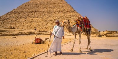 Muž s velbloudem před egyptskou pyramidou