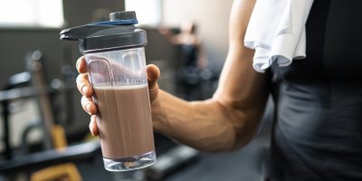 Muž drží proteinový nápoj v shakeru po sportovním tréninku
