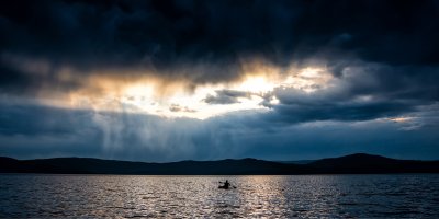Člověk na paddleboardu na vodě během přicházející bouřky