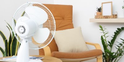 Elektrický ventilátor na stolku vedle křesla