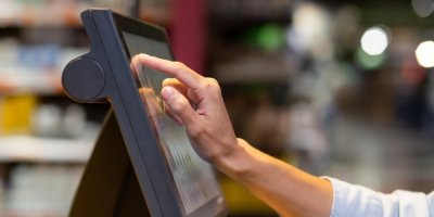 Žena se dotýká obrazovky samoobslužné váhy v supermarketu