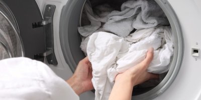 Žena vytahuje bílé prádlo z pračky