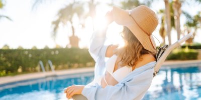 Dívka s kloboukem na hlavě relaxuje u bazénu 