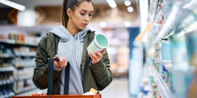 Žena v supermarketu čte etiketu na obalu mléčného produktu