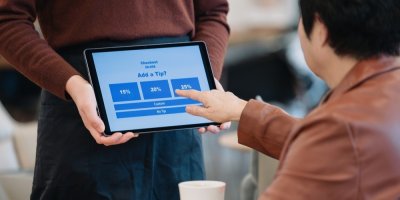 Zákazník v kavárně vybírá výši spropitného na tabletu 