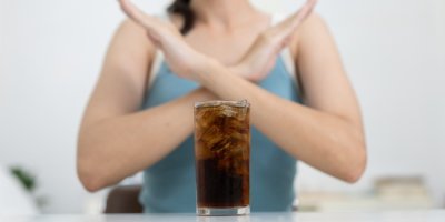 Sklenice Coca-Coly a žena s překříženýma rukama