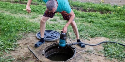 Muž odvádí podzemní vodu na zahradě čerpadlem