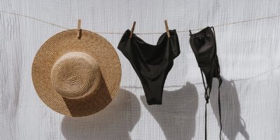 Černé dámské plavky a slaměný klobouk na prádelní šňůře
