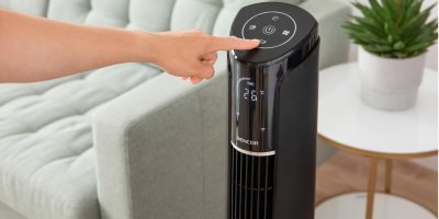 Žena nastavuje sloupový ventilátor v obývacím pokoji