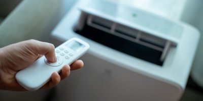 Ruka držící ovladač na mobilní klimatizaci