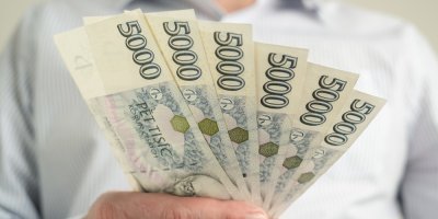 Muž drží v ruce české pětitisícové bankovky