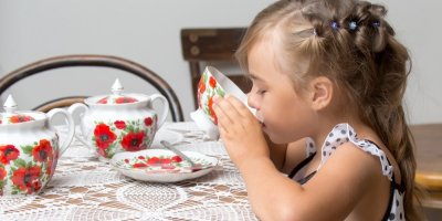 Holčička pije z květovaného porcelánového hrníčku