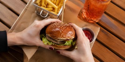 Žena drží hamburger v ruce 