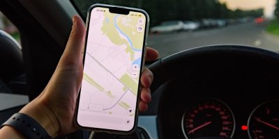 Řidič auta drží v ruce mobilní telefon s navigací
