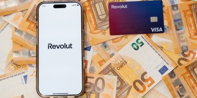Mobilní telefon s logem Revolut, platební karta a eura v bankovkách