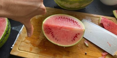 Muž dává palec dolů před rozkrojeným melounem