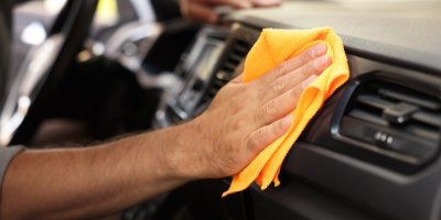 Muž hadříkem čistí interiér auta
