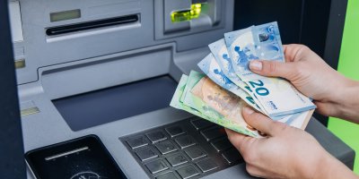 Eurové bankovky před bankomatem