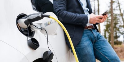 Muž je opřený o nabíjející se auto