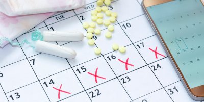 Menstruační tampony leží spolu s pilulkami na kalendáři