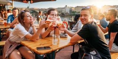 Lidé sedí na venkovní zahrádce u piva