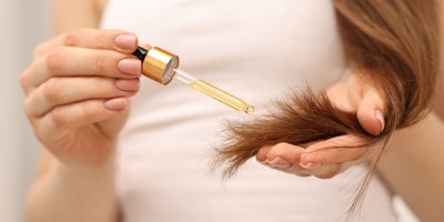 Žena nanáší vlasový olej do konečků vlasů jako součást hair cyclingu