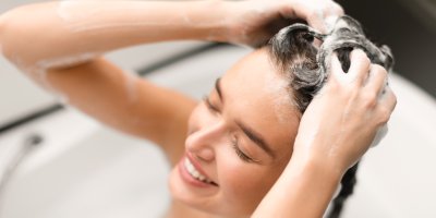 Žena si myje vlasy čisticím šamponem během hloubkového čištění v rámci hair cyclingu