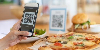 Žena v restauraci provádí mobilní platbu přes QR kód