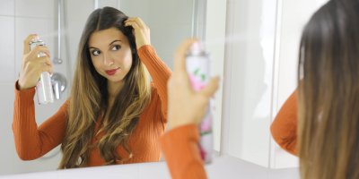 Žena si stříká sprej na vlasy