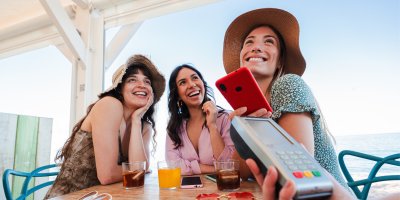 Turistka platí mobilem u platebního terminálu v restauraci
