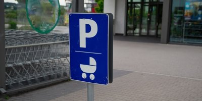 Modrá parkovací značka se symbolem kočárku na parkovišti u supermarketu