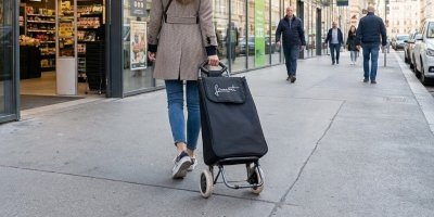Mladá žena jde s taškou po ulici 