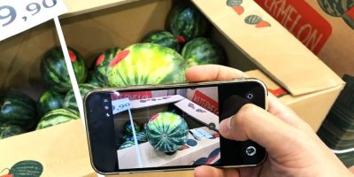 Muž fotí mobilním telefonem vodní meloun v supermarketu