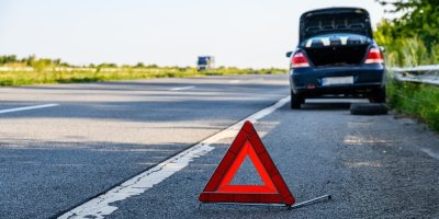 Výstražný trojúhelník a auto stojící na krajnici