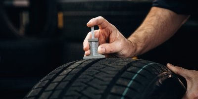 Technik měří hloubku dezénu na pneumatice