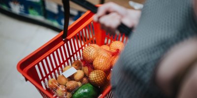Žena v supermarketu drží nákupní košík s ovocem